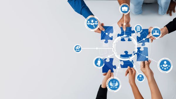Collaborative Teamwork Concept with Puzzle Pieces, Hands Reaching for Solutions, and Interactive Connectivity in a Modern Workspace Environment. Amity